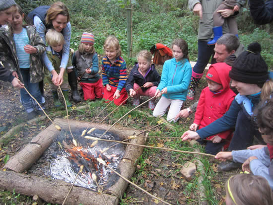 Group of children and adults toasting bread over a fire