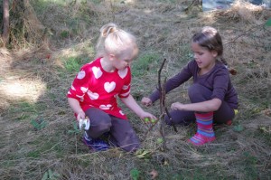 two girls creating a pixie house from twigs