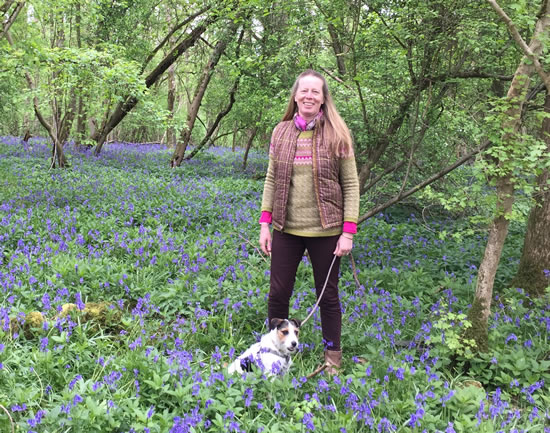woman with dog standing in bluebells