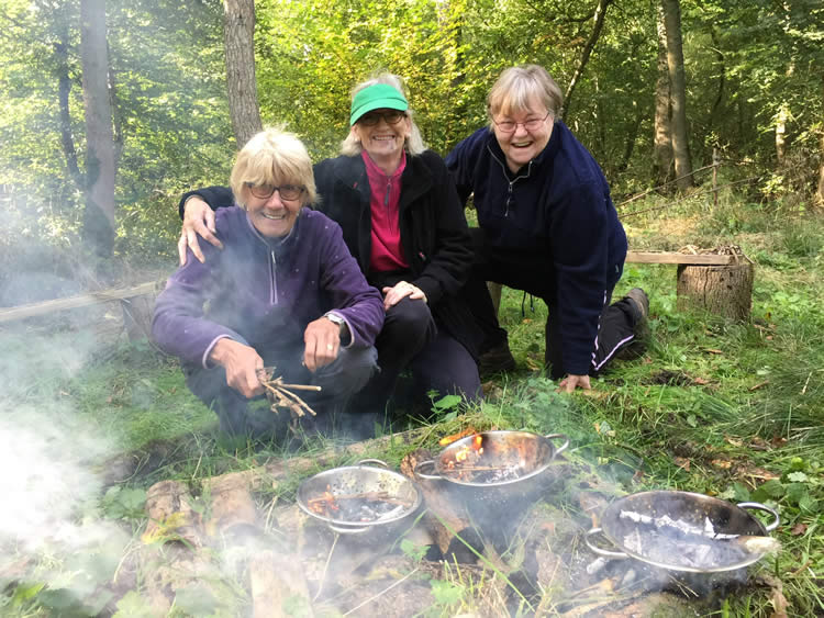 three ladies by a camp fire