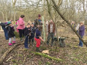 adults and children planting trees in woodland