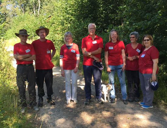 men and women in red t shirts standing in woodland